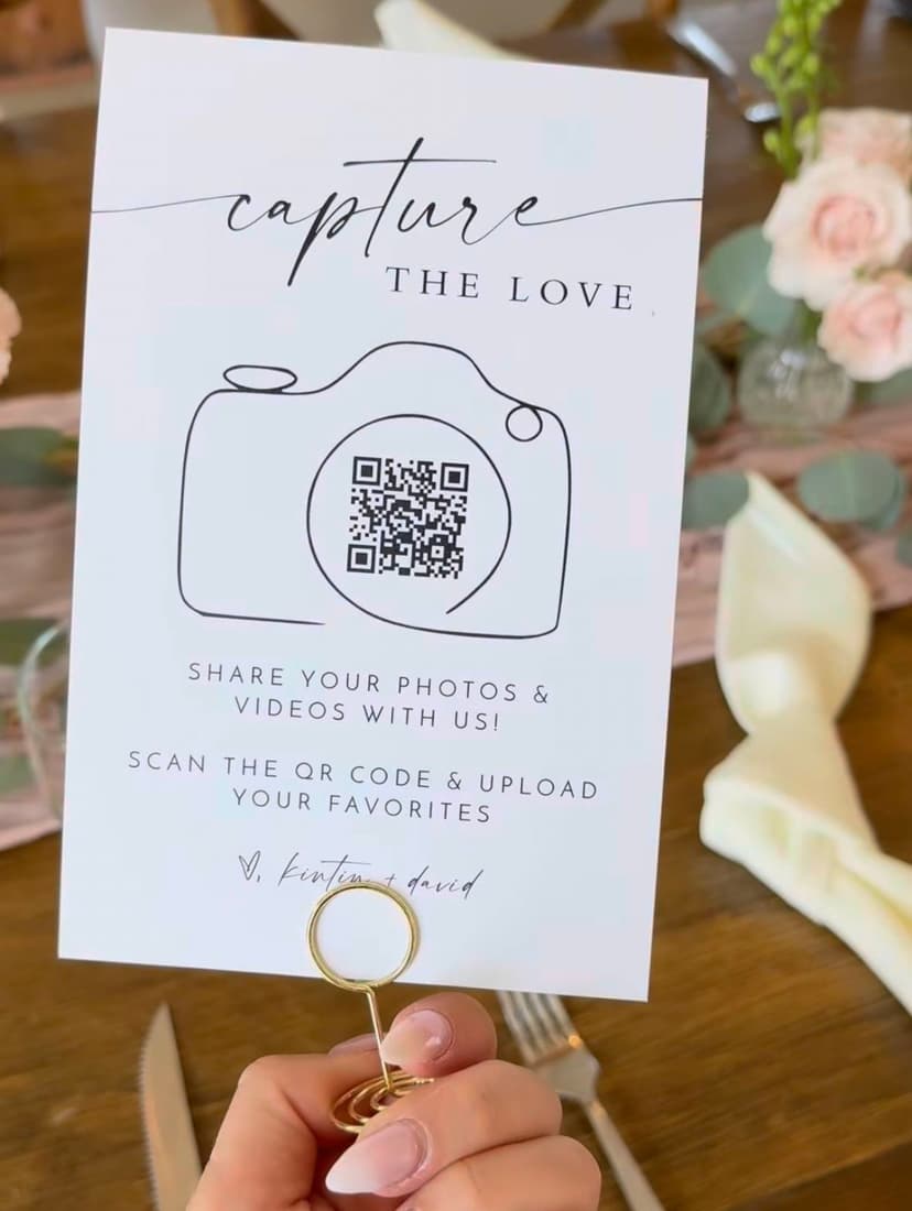 Carte QR code de mariage tenue à une réception — carte 'Capture the Love' imprimée que les invités scannent pour partager leurs photos